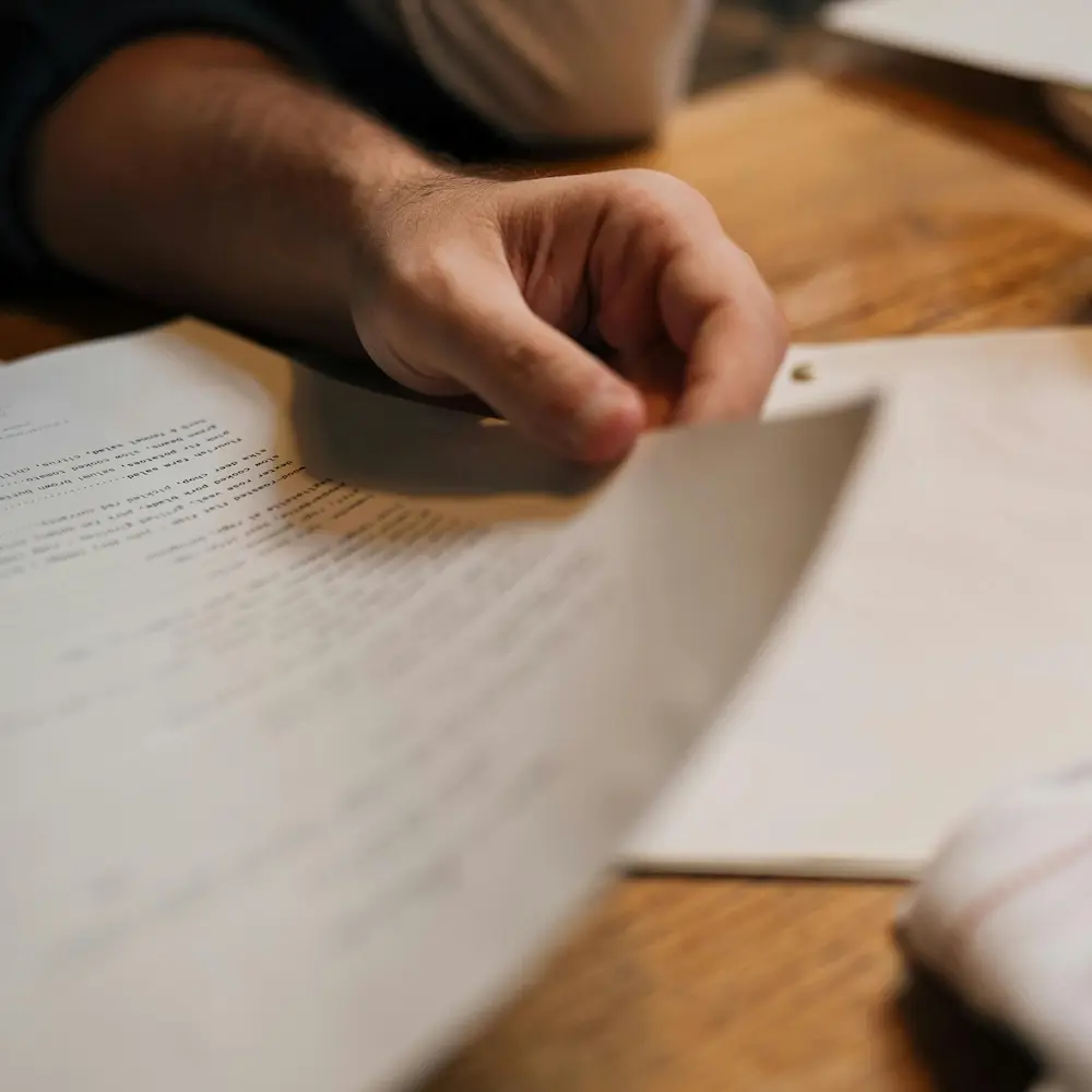 Gros plan sur une main consultant un document papier, illustrant les pièces administratives obligatoires (carte grise, pièce d'identité, certificats) à préparer pour l'enlèvement de votre véhicule